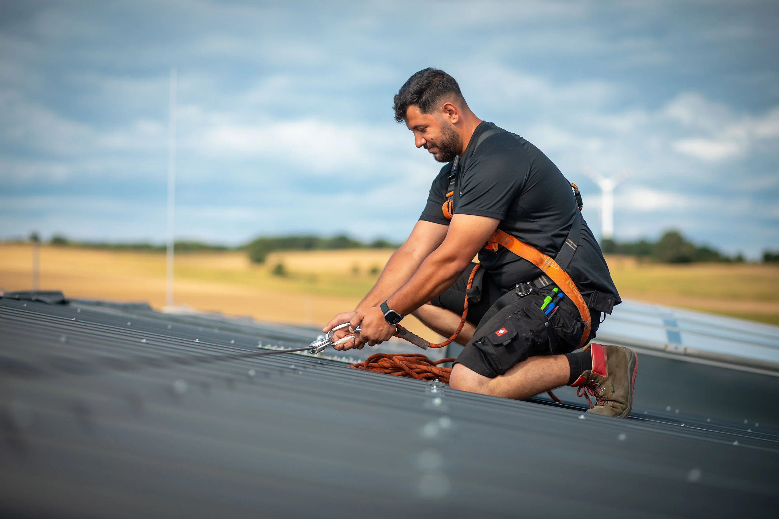 Mann mit Absturz­sicherung auf dem Dach