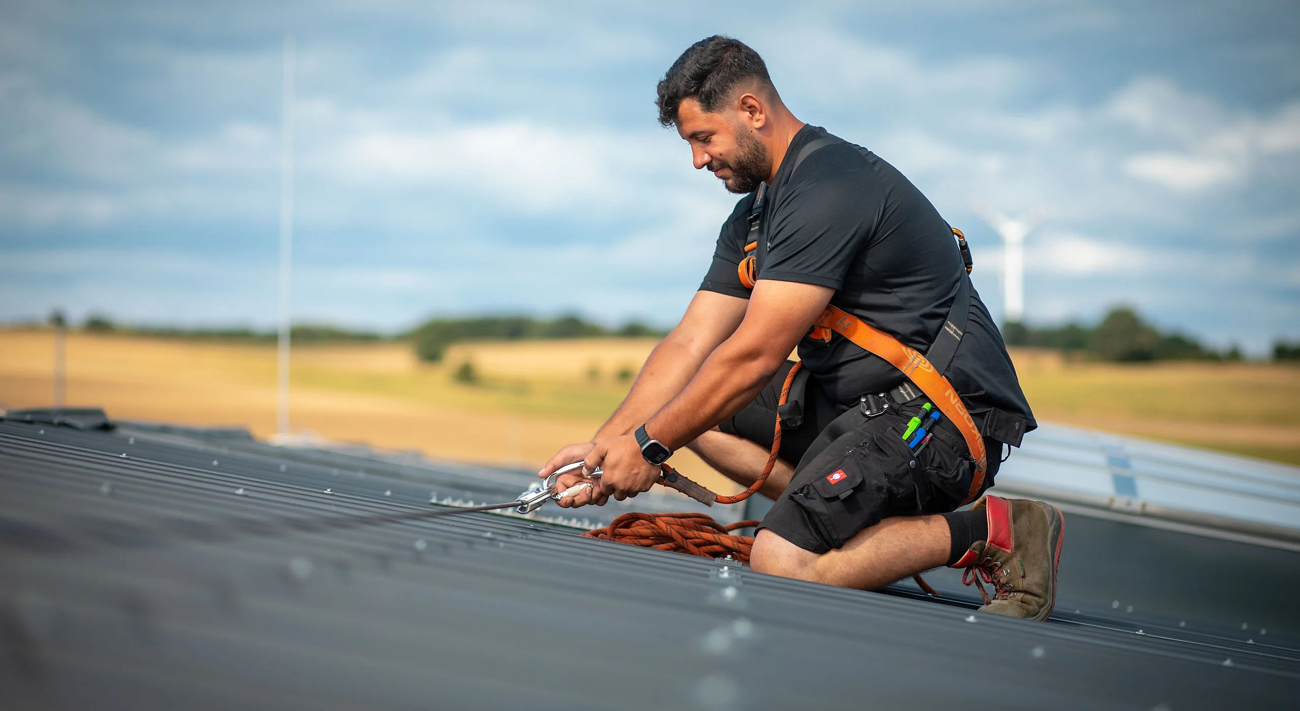 Mann mit Absturz­sicherung auf dem Dach