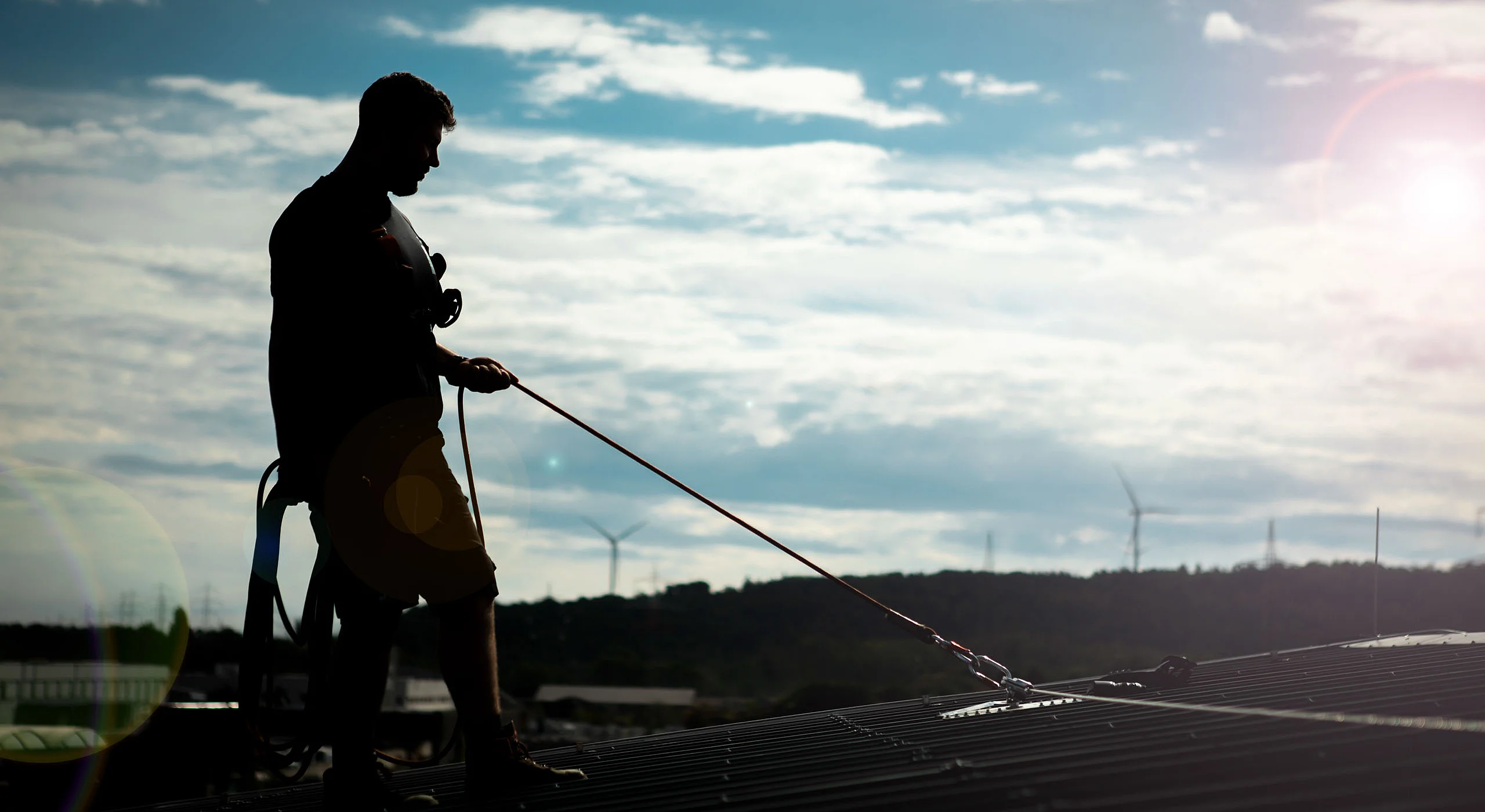 Mann mit Absturz­sicherung auf dem Dach