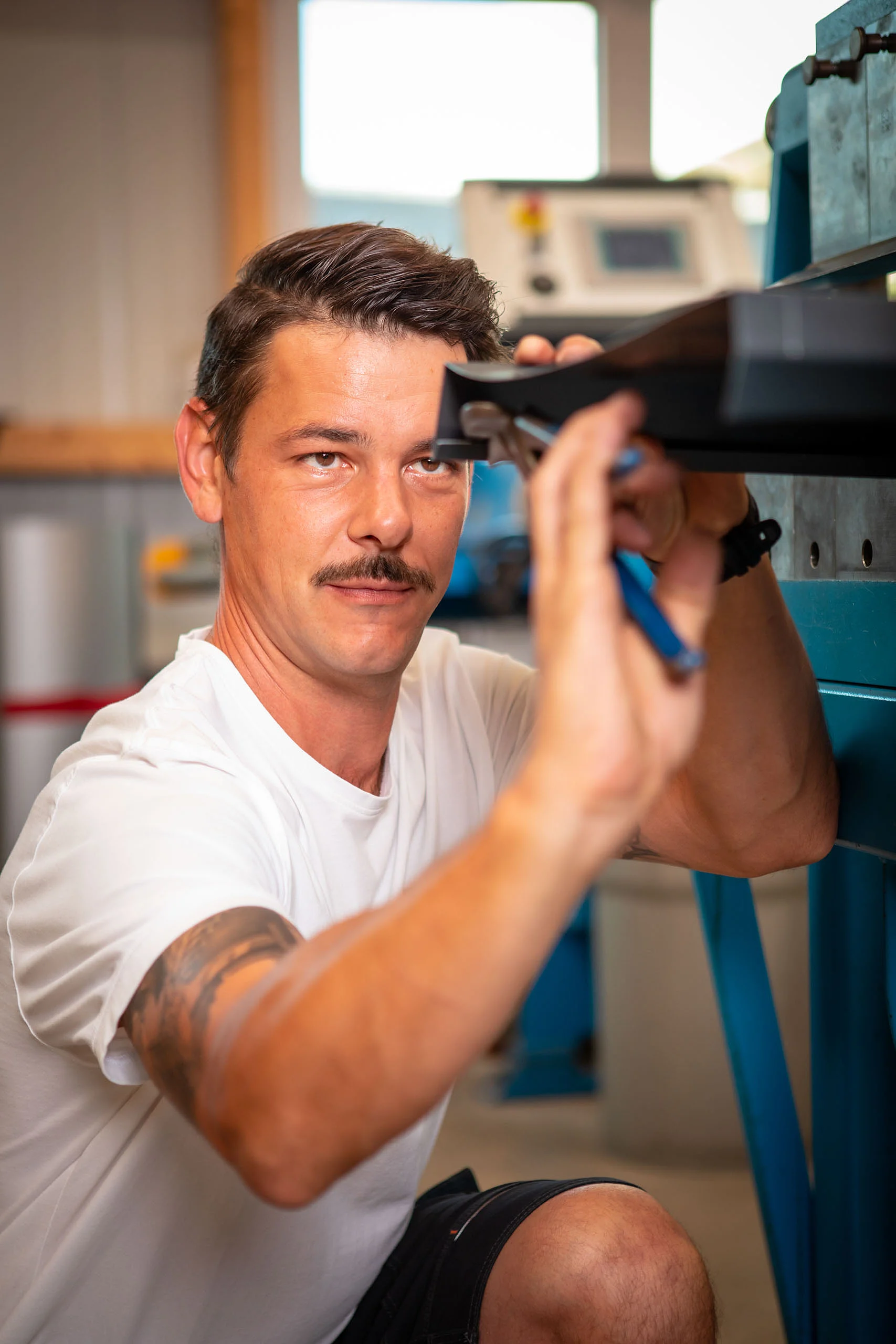 Mitarbeiter biegt ein Blechstück zurecht