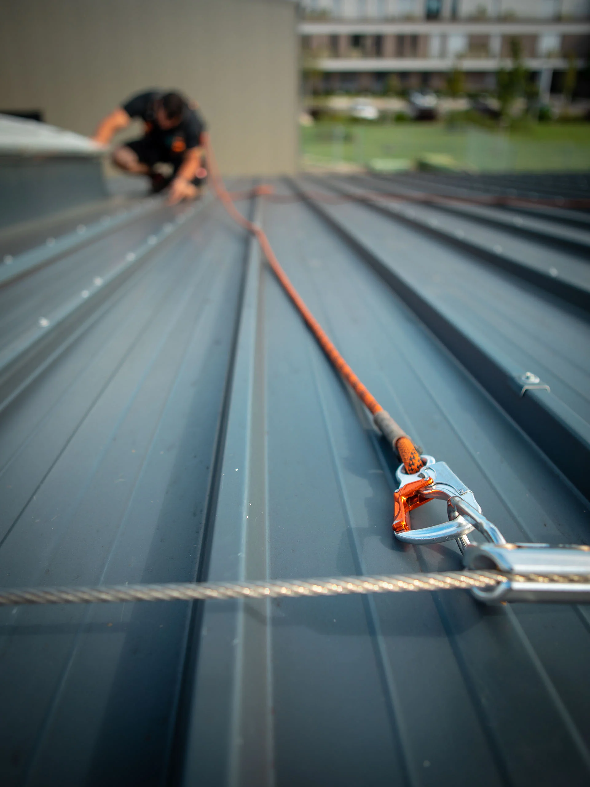 Mann mit Absturz­sicherung auf dem Dach