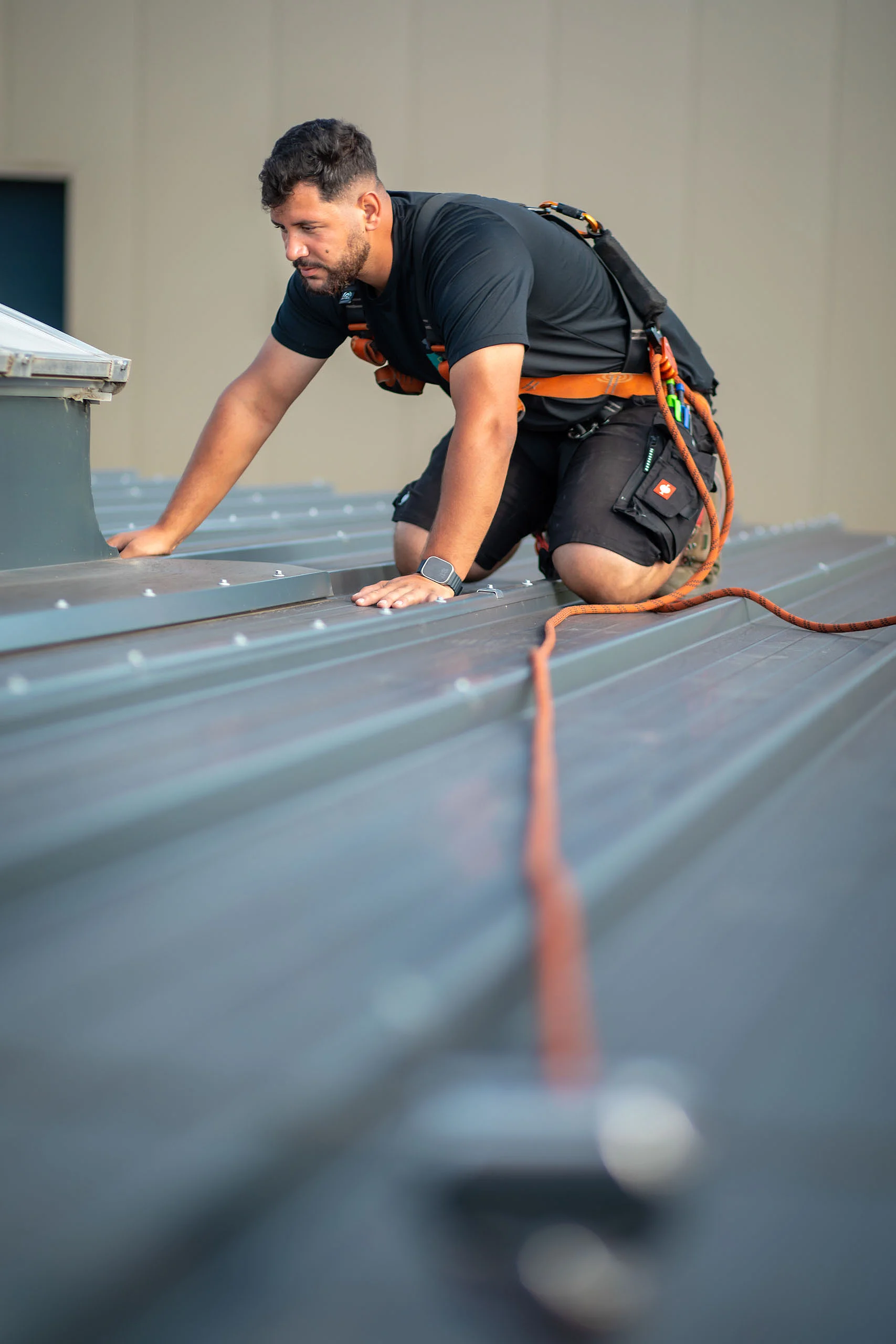 Mann mit Absturz­sicherung auf dem Dach