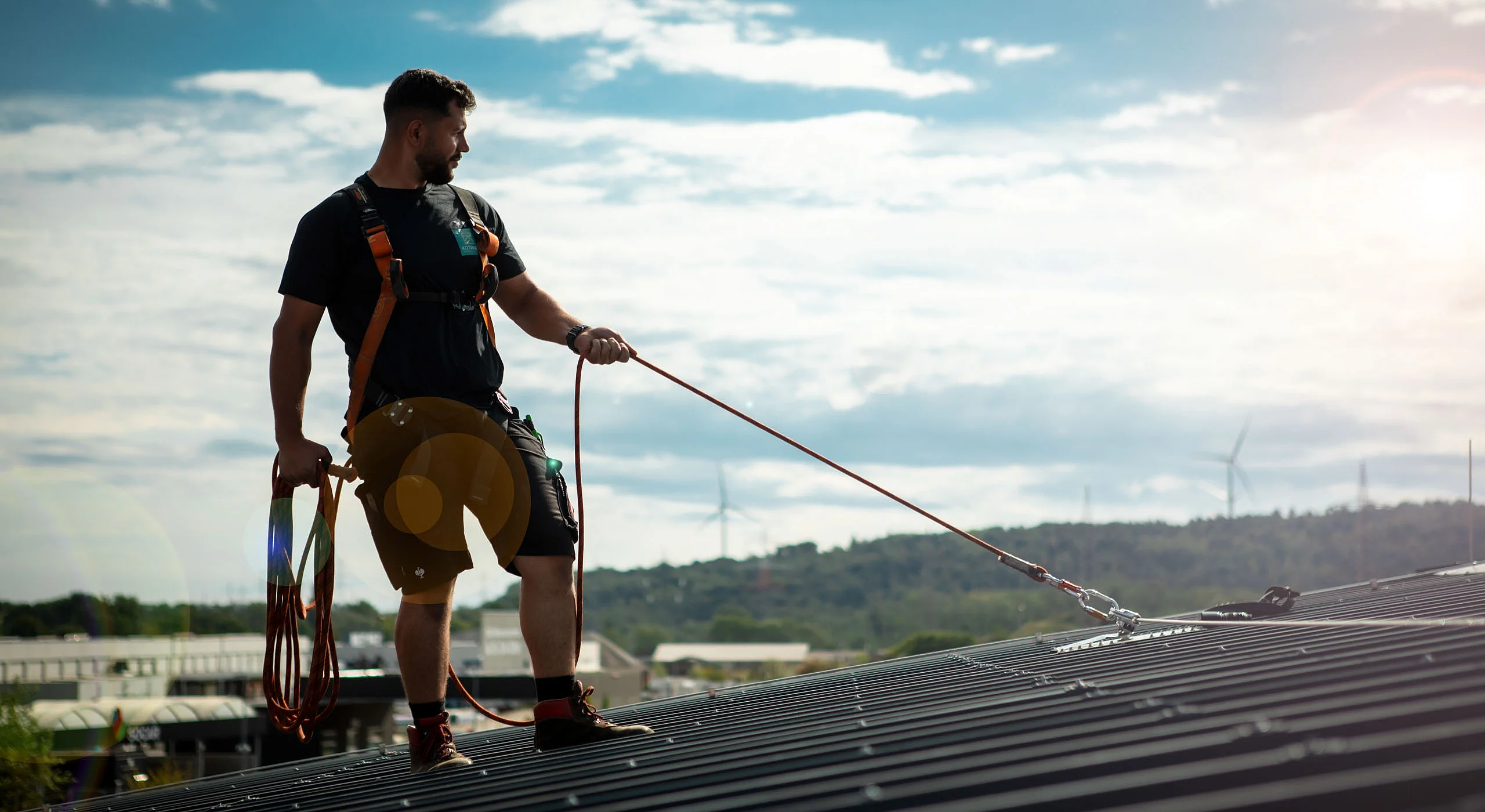 Mann mit Absturz­sicherung auf dem Dach