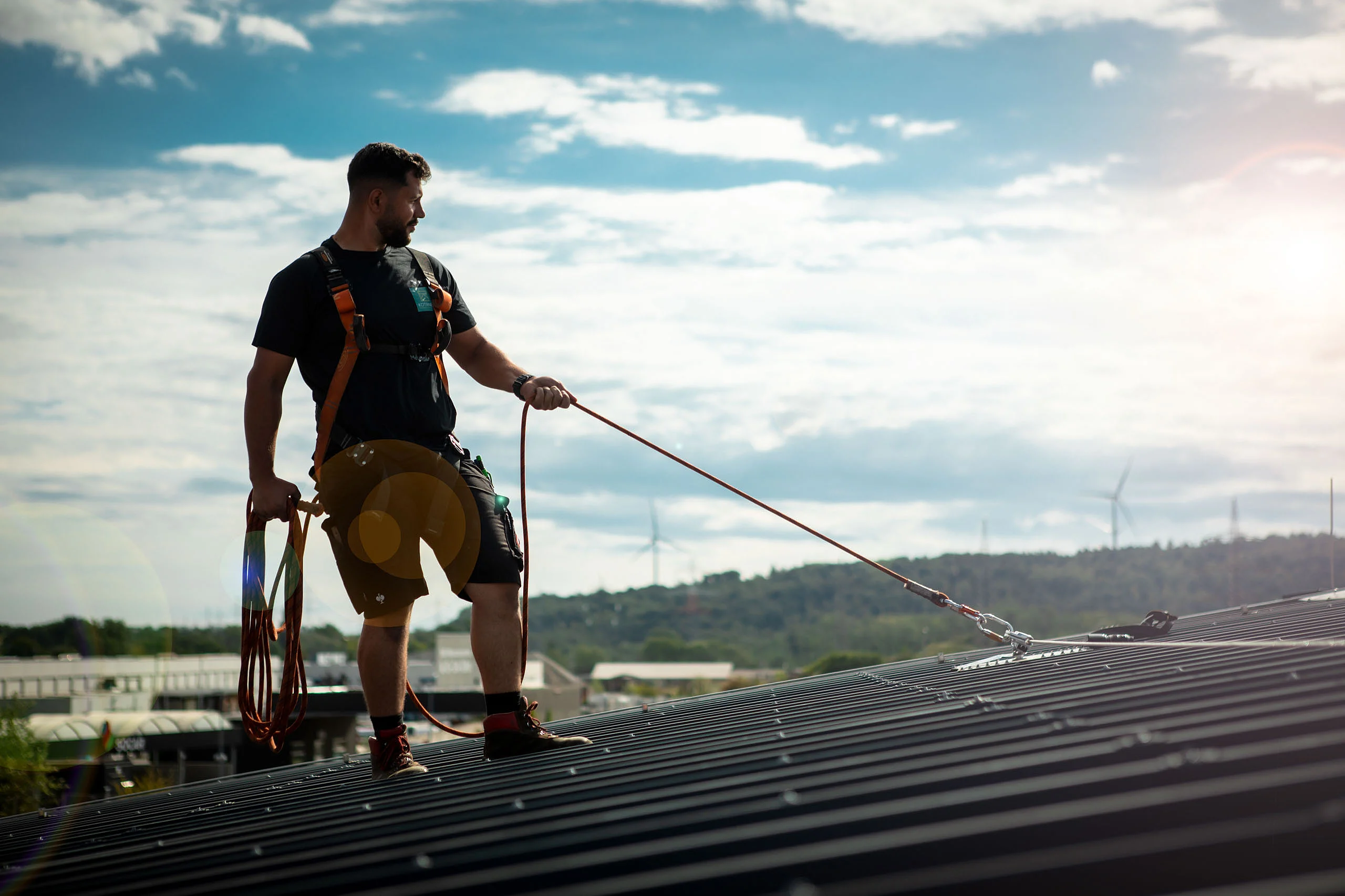 Mann mit Absturz­sicherung auf dem Dach