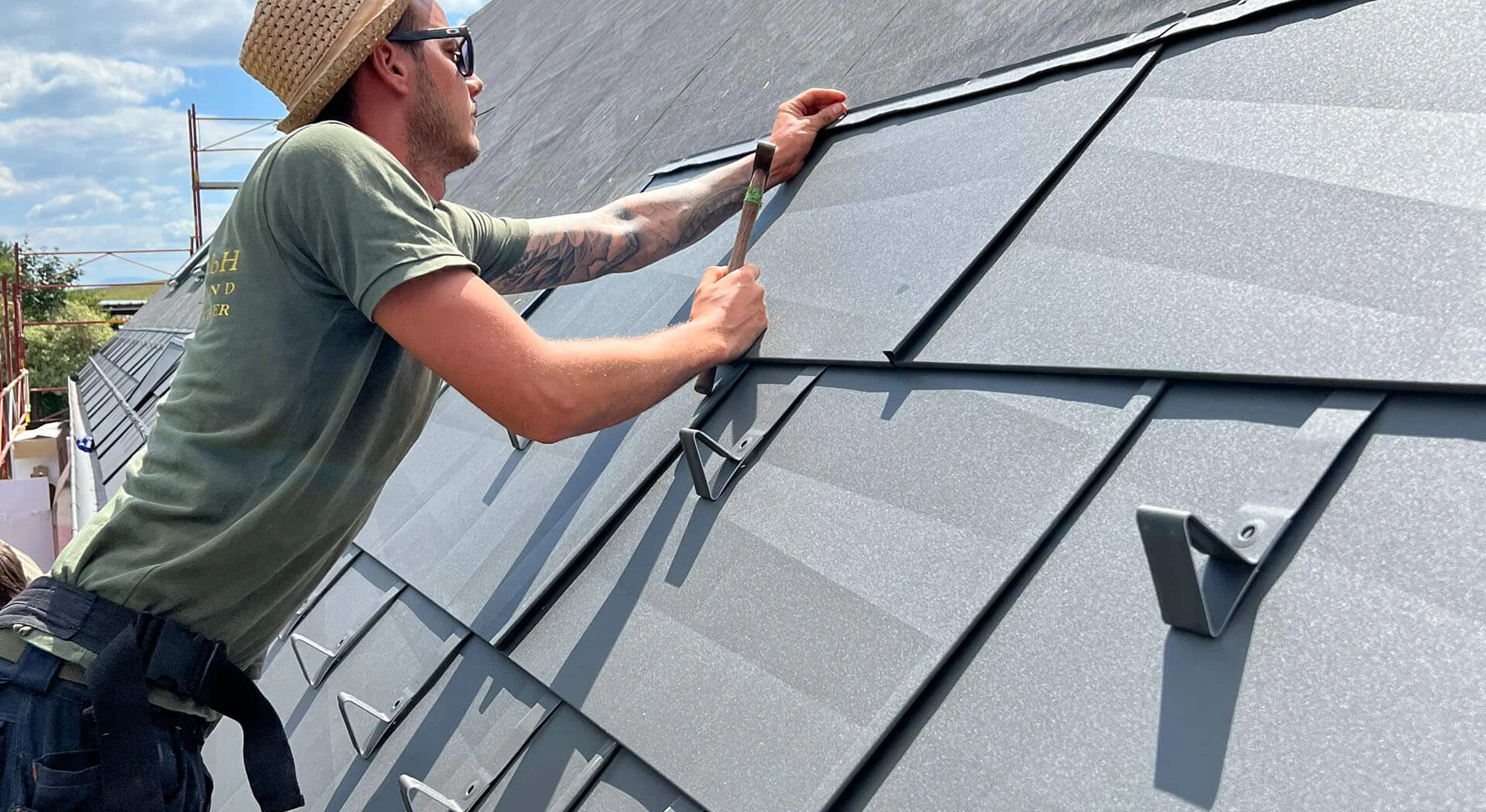Spengler befestigt Blechplatten auf ein Dach
